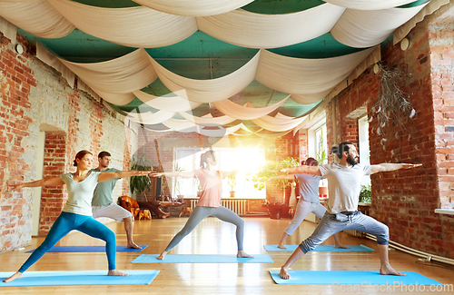 Image of group of people doing yoga warrior pose at studio