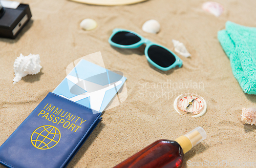 Image of travel tickets, camera and hat on beach sand