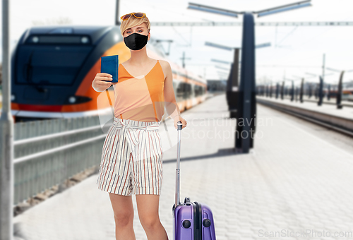 Image of woman in mask with travel bag over train