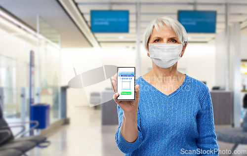 Image of old woman with certificate of vaccination on phone