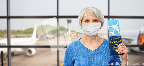 Image of old woman in mask with immune passport and ticket