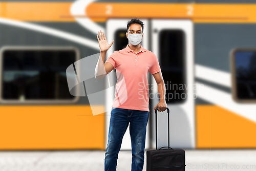 Image of indian man in mask with travel bag waving hand