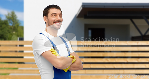 Image of happy male worker or cleaner in overall and gloves