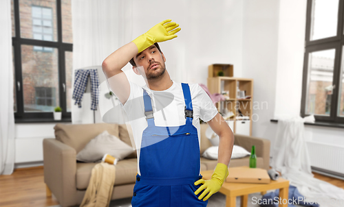 Image of tired male worker or cleaner in gloves at home