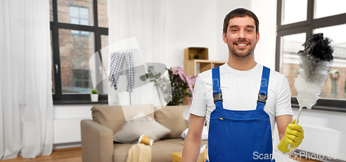 Image of happy male cleaner with duster cleaning home room