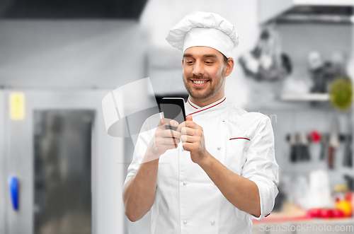 Image of happy smiling male chef with smartphone at kitchen