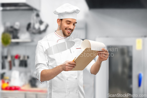 Image of happy smiling male chef with clipboard at kitchen