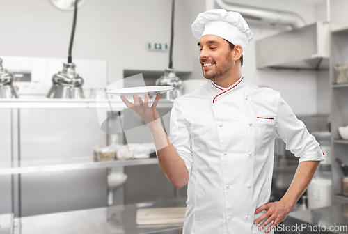 Image of happy smiling male chef holding empty plate