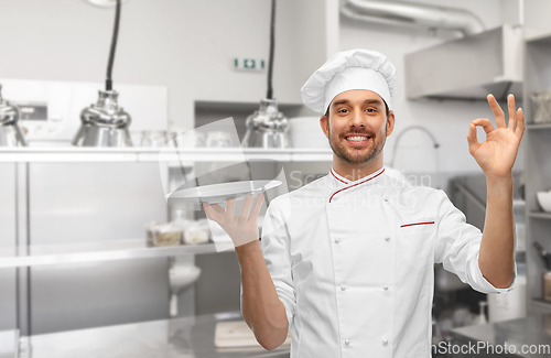 Image of happy smiling male chef holding empty plate