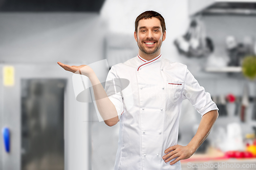 Image of happy smiling male chef holding something on hand