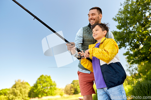 Image of happy smiling father and son fishing on river