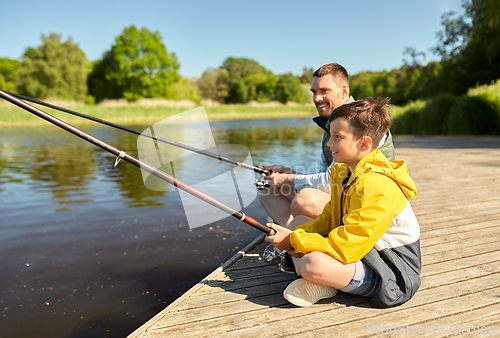 Image of happy smiling father and son fishing on river