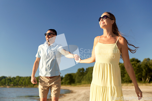 Image of happy couple holding hands on summer beach