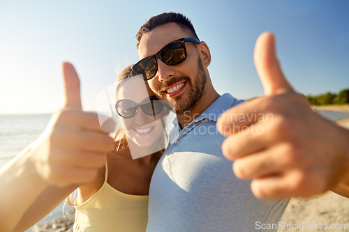 Image of happy couple showing thumbs up on summer beach