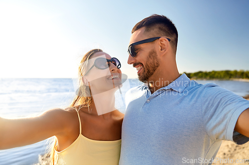 Image of happy couple taking selfie on summer beach