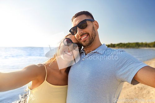 Image of happy couple taking selfie on summer beach