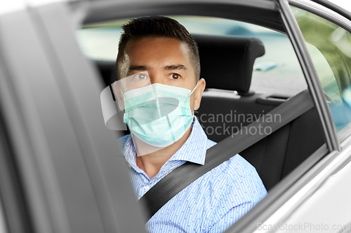 Image of man or male passenger wearing mask in car