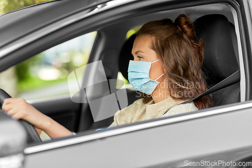 Image of woman or female driver in mask driving car in city