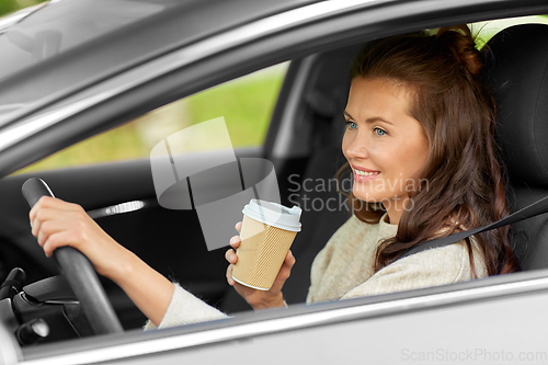 Image of woman or female driver with coffee driving car