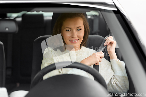 Image of woman or female car driver fastening seat belt