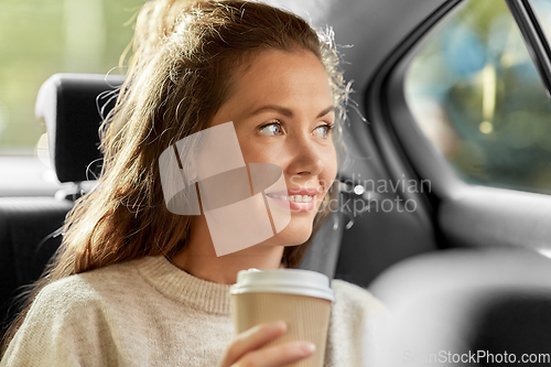 Image of smiling woman or passenger drinking coffee in car