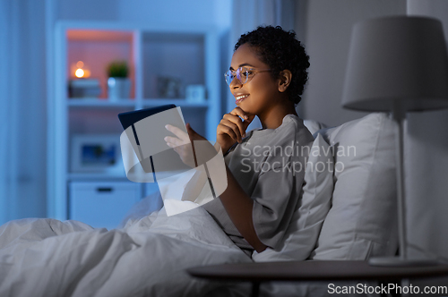 Image of woman with tablet pc in bed at home at night