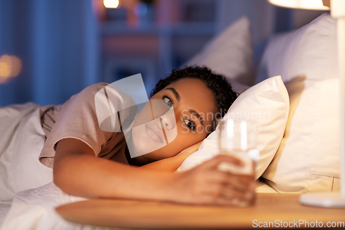 Image of african american woman drinking water at night