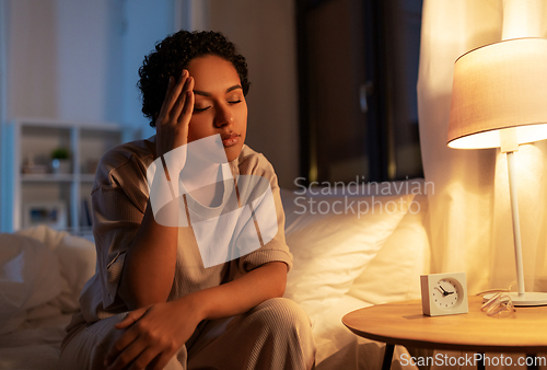 Image of stressed african woman lying in bed at night