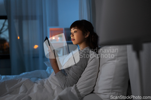 Image of asian woman with tablet pc in bed at home at night