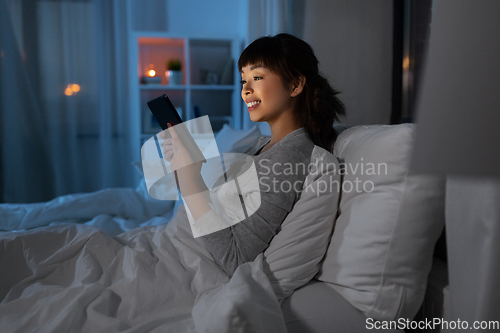 Image of asian woman with tablet pc in bed at home at night