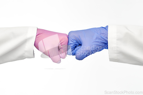 Image of hands of doctors in gloves make fist bump gesture