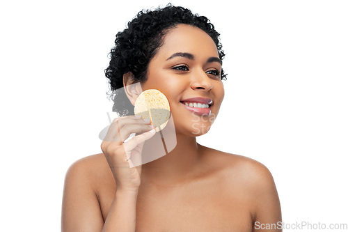 Image of young woman cleaning face with exfoliating sponge