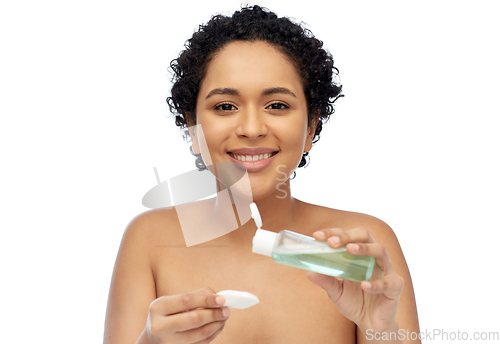 Image of happy african woman with cotton pad an lotion