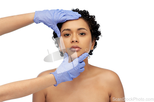 Image of face of african woman and hands in medical gloves