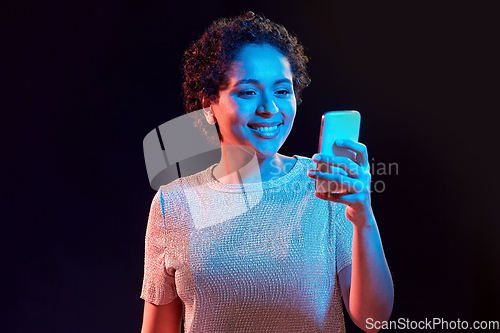 Image of african woman with smartphone in neon lights