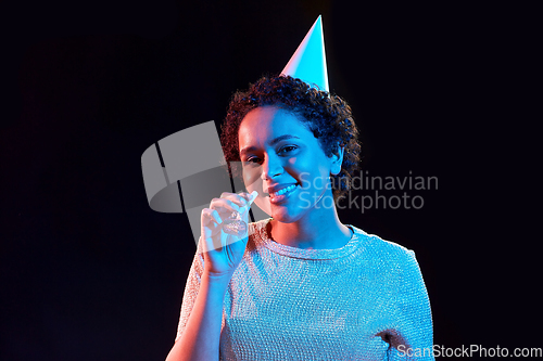 Image of african woman in party cap with blower over black