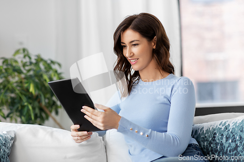 Image of happy smiling young woman with tablet pc at home