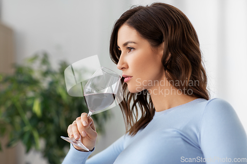 Image of happy woman drinking red wine at home