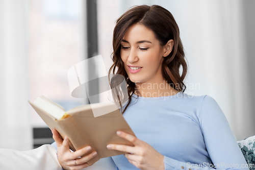 Image of young woman reading book at home