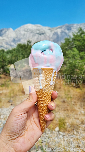 Image of Melting gelato ice cream cone held up to the hot summer day