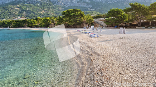 Image of Beautiful shore of the Adriatic Sea. Bay view with beach and deck chairs. Sunrise