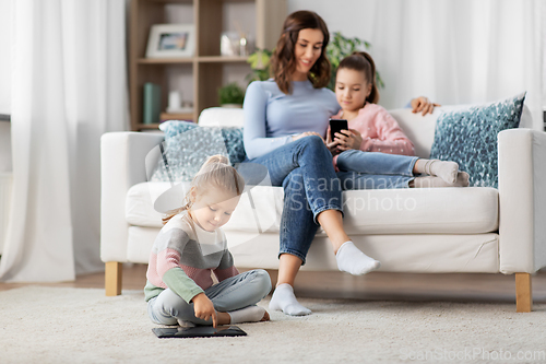 Image of happy mother and daughters with smartphone at home