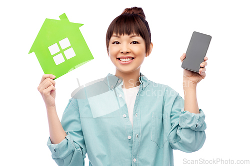 Image of smiling asian woman holding green house