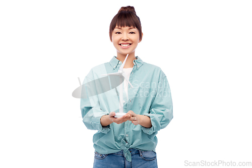 Image of smiling young asian woman with toy wind turbine