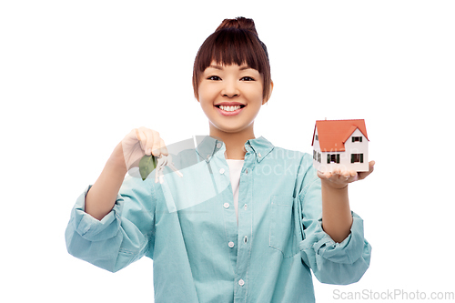 Image of smiling asian woman holding house model and keys