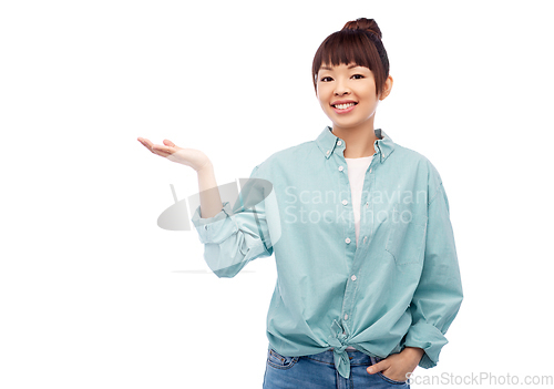 Image of happy asian woman holding something on hand