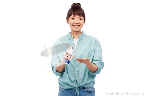 Image of happy smiling asian woman using hand sanitizer