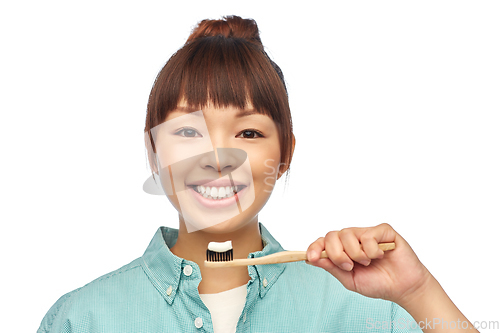 Image of asian woman with toothpaste on wooden toothbrush