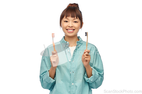 Image of asian woman with wooden and plastic toothbrushes