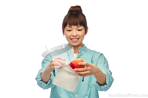 Image of happy woman putting apple into reusable bag